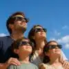 Famille portant des lunettes de protection pour éclipse solaire Grez Optic regardant le ciel